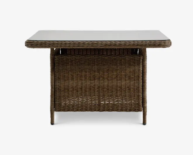 Rektangulært bord med en glat, lys bordplade og en robust base af flettet rattan. Bordet har afrundede hjørner og en solid flettet panel på den ene side, hvilket giver både stabilitet og et dekorativt udtryk. Benene er også omviklet med rattan, hvilket giver bordet et ensartet, naturligt look, der egner sig til både indendørs og udendørs brug.