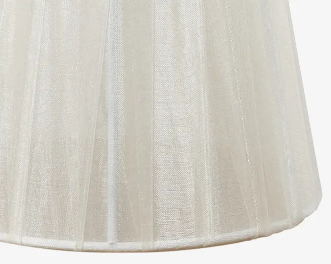 Nærbillede af et halvgennemsigtigt, råhvidt stof med let glans, arrangeret i lodrette paneler. Materialet virker let og en smule tekstureret, med synlige syninger hvor panelerne mødes. Formen er let udvidet forneden, hvilket giver et struktureret men blødt udtryk.