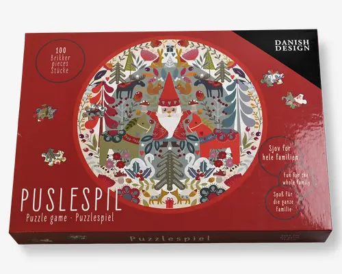 Æsken har en festlig, cirkulær illustration med en nisse i rød hue og frakke i midten, omgivet af stiliserede skovdyr som hjorte, ræve, svaner og fugle samt træer og dekorative elementer i røde, grønne og hvide nuancer. Puslespillet består af 100 brikker og har et skandinavisk design. Emballagen fremhæver, at det er sjovt for hele familien og understreger det danske design.