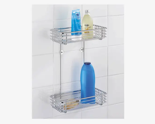 Et to-etagers vægmonteret brusehylde i blankt krombelagt metal med trådramme-design. Hylden har to rektangulære kurve, placeret oven på hinanden, som giver god opbevaringsplads til flasker og toiletartikler. Kurvene har høje sider, der forhindrer ting i at falde ud, og enheden er fastgjort til en flisevæg med synlige skruer for sikker montering.