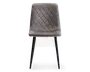 Stol med polstret sæde og ryglæn betrukket med blødt, gråt velourstof. Ryglænet og sædet har et quiltet design med diamantmønster, som giver ekstra struktur og stil. Stolen står på fire slanke, sorte metalben, der smalner let ind mod gulvet og giver et moderne og elegant udtryk.
