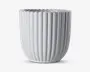 En hvid keramisk beholder med blank overflade, lodrette riller og bølget kant. Designet er moderne og elegant med en cylindrisk form, der smalner let ind mod bunden.