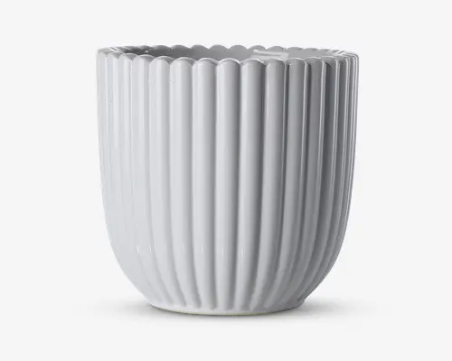 En hvid keramisk beholder med blank overflade, lodrette riller og bølget kant. Designet er moderne og elegant med en cylindrisk form, der smalner let ind mod bunden.