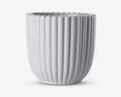 En hvid keramisk beholder med blank overflade, lodrette riller og bølget kant. Designet er moderne og elegant med en cylindrisk form, der smalner let ind mod bunden.