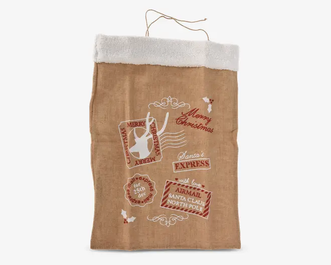 Stor brun sæk med hvidt kunstpelskant øverst og snorehåndtag. Forsiden er dekoreret med festlige tryk, herunder et rensdyrstempel, kristtornblade og tekster som 'Merry Christmas', 'Santa's Express' og 'Airmail Santa Claus North Pole'. Designet har et vintage posttema med røde og hvide detaljer.