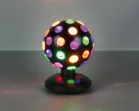 Sfærisk lampe med sort fod og krop, udstyret med flere runde linser i forskellige farver som rød, grøn, gul og lilla. Lampen udsender farverigt lys gennem linserne og skaber en livlig, flerfarvet effekt. Basen er solid og let facet, og understøtter det roterende kugledesign.