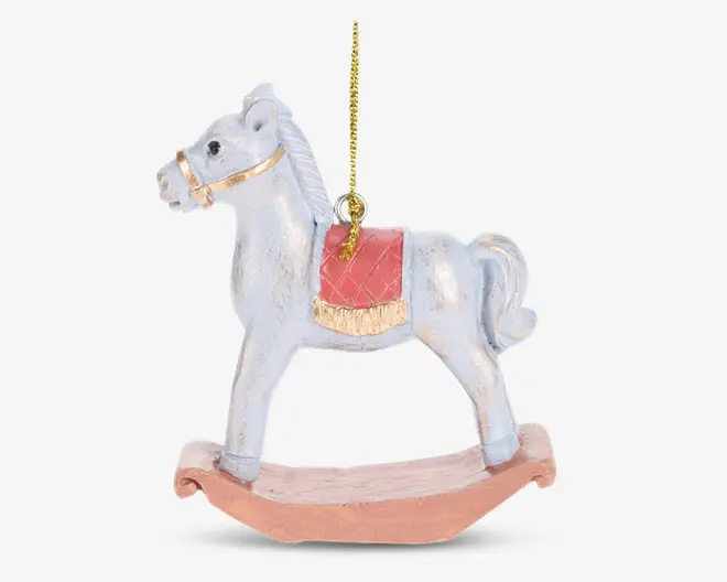 En dekorativ gyngehest-ornament med en hvid hest, der har et gyldent hovedtøj og en rød sadel med guldfarvet kant. Hesten står på en buet, lysebrun gyngebase og har en gylden ophængssnor fastgjort på toppen til nem ophængning.