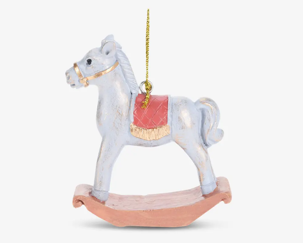 En dekorativ gyngehest-ornament med en hvid hest, der har et gyldent hovedtøj og en rød sadel med guldfarvet kant. Hesten står på en buet, lysebrun gyngebase og har en gylden ophængssnor fastgjort på toppen til nem ophængning.