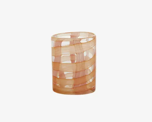 Et cylindrisk glas med en glat, blank overflade. Glasset har et karakteristisk design med brede, snoede bånd i gennemsigtige fersken- og beige nuancer, der slynger sig rundt om glasset. Kanten er let afrundet, og det samlede udtryk er moderne og kunstnerisk, hvilket gør det velegnet både til daglig brug og som dekoration.