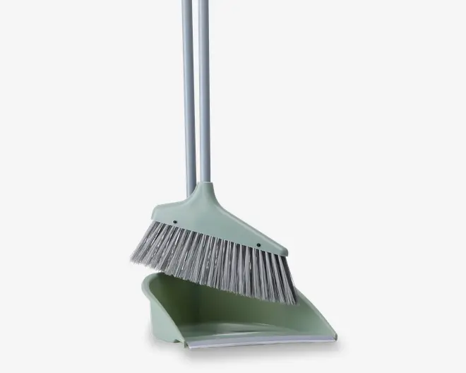 Et rengøringssæt bestående af en kost med bløde, skrå børster og en matchende fejebakke. Begge dele har lange, sølvfarvede håndtag, så de er behagelige at bruge stående. Fejebakken har en bred åbning og en flad kant, der gør det nemt at samle snavs op. Sættet er i en afdæmpet grøn farve.