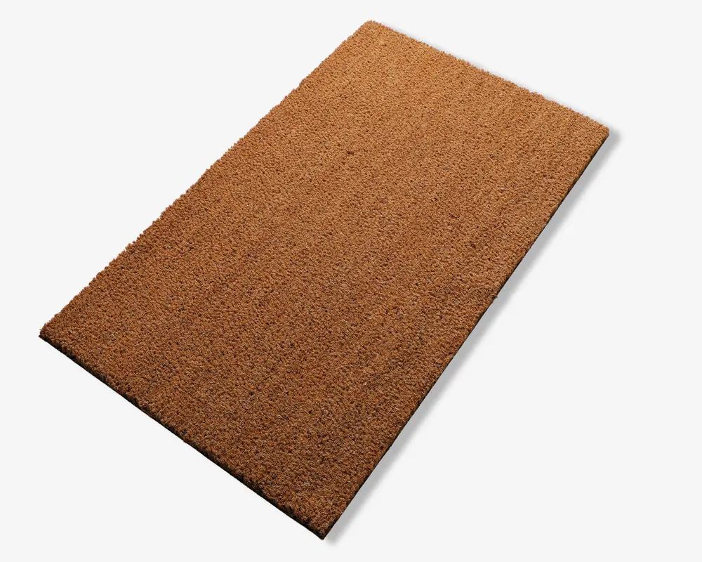 Rektangulær måtte med en grov, tekstureret overflade i en naturlig brun farve. Måtten ser ud til at være lavet af slidstærkt, fiberrigt materiale, sandsynligvis kokos, og har rene, lige kanter. Den er designet til effektivt at fjerne snavs og skidt fra sko.