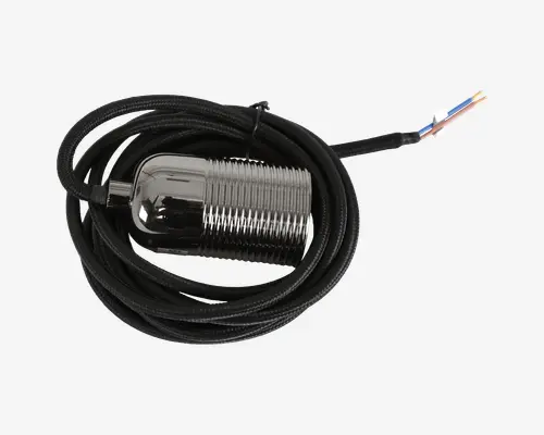 Cylindrisk sensor i metal med riflet, gevindskåret krop til sikker montering. Sensoren er forbundet til et langt, sort flettet kabel, som ender i tre afisolerede, farvekodede ledninger (blå, brun og sort) til elektrisk tilslutning. Det metalliske hus har en blank, reflekterende overflade, og kablet er rullet sammen for nem opbevaring eller installation.