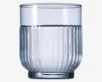 Klar glastumbler med cylindrisk form og lodret rillet tekstur på den nederste halvdel. Glasset har en tyk, solid bund og glat kant, og er delvist fyldt med vand. Det rillede design giver et godt greb og et dekorativt udtryk.