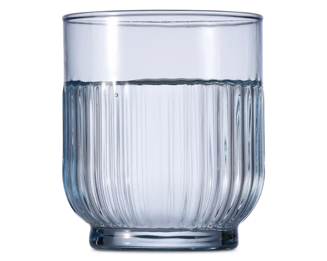 Klar glastumbler med cylindrisk form og lodret rillet tekstur på den nederste halvdel. Glasset har en tyk, solid bund og glat kant, og er delvist fyldt med vand. Det rillede design giver et godt greb og et dekorativt udtryk.