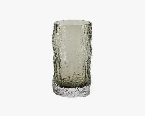 Høj, cylindrisk glas med en tekstureret, hamret overflade, der giver et bølget udseende. Glasset er gennemsigtigt med en let røgfarvet tone, og bunden er tyk og klar, hvilket giver stabilitet og et moderne udtryk.