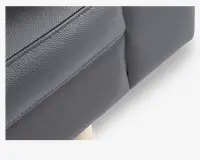 Nærbillede af et stykke mørkegråt kunstlæderbetræk med synlige syninger og let tekstureret overflade. Billedet fremhæver materialets struktur og den pæne søm, hvilket indikerer en veludført og holdbar finish.