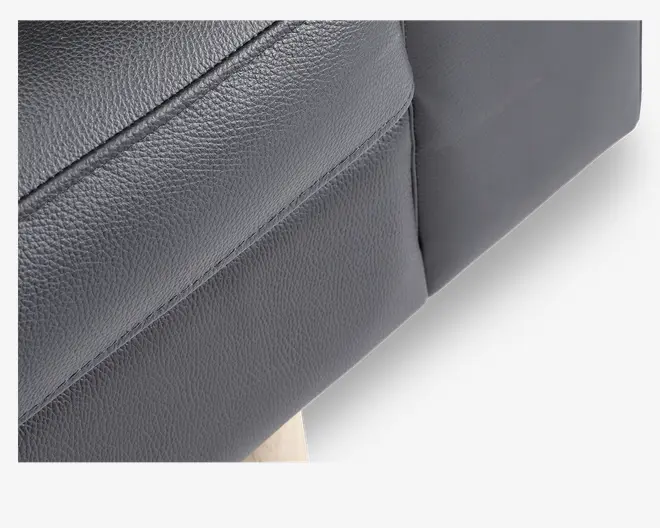 Nærbillede af et stykke mørkegråt kunstlæderbetræk med synlige syninger og let tekstureret overflade. Billedet fremhæver materialets struktur og den pæne søm, hvilket indikerer en veludført og holdbar finish.