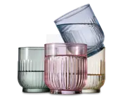 Sæt med fire lave drikkeglas, hver med rillet tekstur og en let rundet form. Glassene har forskellige transparente farver: lysegrøn, pink, gul og blå. Designet har lodrette riller, hvilket giver et stilfuldt og moderne udtryk.