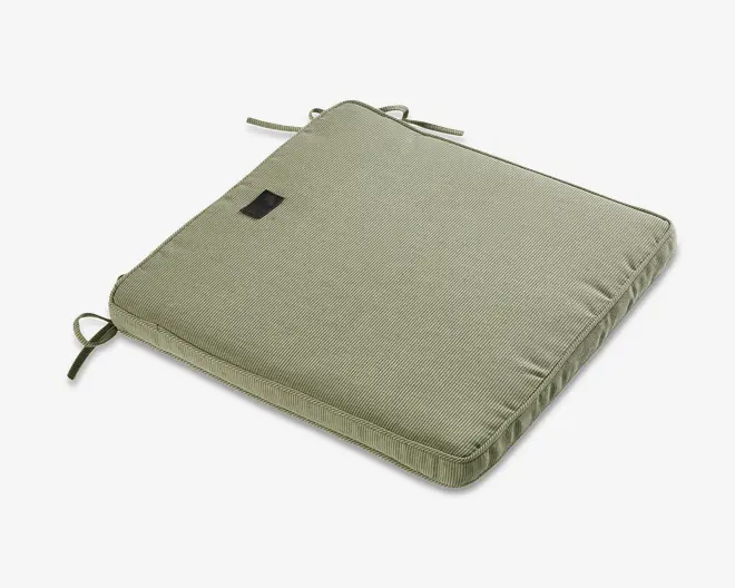 Firkantet pude i en afdæmpet grøn farve med diskret stribet tekstur. Puden har to sæt stofsnore i hjørnerne, så den kan fastgøres til en stol. Den er let polstret for ekstra komfort og har et lille, rektangulært mærke syet på oversiden.