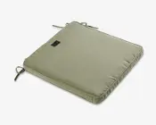 Firkantet pude i en afdæmpet grøn farve med diskret stribet tekstur. Puden har to sæt stofsnore i hjørnerne, så den kan fastgøres til en stol. Den er let polstret for ekstra komfort og har et lille, rektangulært mærke syet på oversiden.