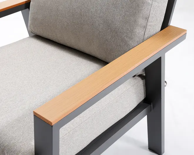 Nærbillede af en stol med lysegrå, teksturerede stofhynder på både sæde og ryg. Stellet er lavet af mørkegråt metal med lige, rene linjer, og armlænene har en glat overflade i lyst træ, hvilket giver en moderne og stilfuld kontrast. Hynderne ser tykke og komfortable ud, og det samlede design fremstår moderne og robust.