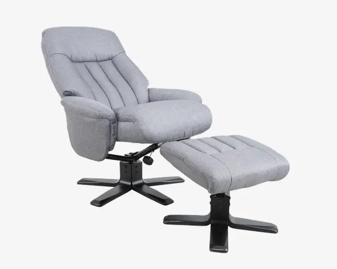 En moderne lænestol med tilhørende fodskammel, begge betrukket med lysegråt stof. Stolen har polstrede armlæn, høj ryg med lodrette syninger og en tyk, blød siddepude. Både stol og skammel har solide sorte metalbaser med fire ben for stabilitet.