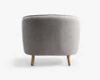 Rund puf med lysegråt tekstureret stofbetræk, har en glat, sømløs overflade og står på tre korte, cylindriske træben med naturfinish.