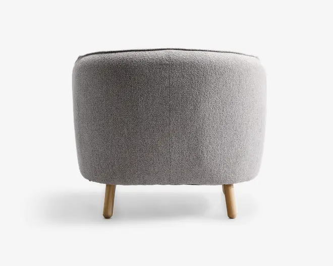 Rund puf med lysegråt tekstureret stofbetræk, har en glat, sømløs overflade og står på tre korte, cylindriske træben med naturfinish.