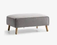Rektangulær puf med lysegråt tekstureret stofbetræk, afrundede kanter og fire skråtstillede træben i naturfarve. Designet er minimalistisk og moderne, velegnet til nutidige indretninger.