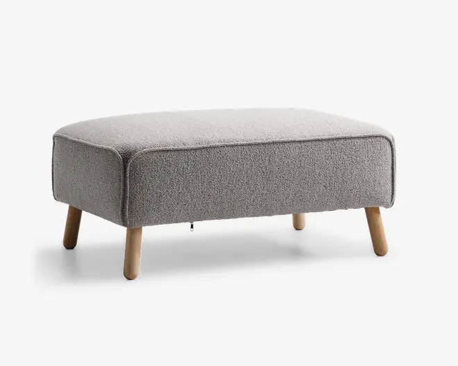 Rektangulær puf med lysegråt tekstureret stofbetræk, afrundede kanter og fire skråtstillede træben i naturfarve. Designet er minimalistisk og moderne, velegnet til nutidige indretninger.