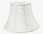 En klokkeformet lampeskærm lavet af hvidt stof med en diskret krøllet tekstur. Skærmen har lodrette stofpaneler adskilt af smalle bånd, og både øverste og nederste kant er afsluttet med en glat, afrundet stofkant. Udtrykket er klassisk og elegant, velegnet til traditionel eller tidløs indretning.