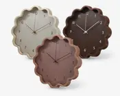 Tre vægure med bølgede, scallop-formede kanter og minimalistisk design. Hvert ur har en forskellig farve: creme, brun og støvet rosa. Urskiven har enkle, letlæselige arabiske tal og slanke time-, minut- og sekundvisere. Skiven er uden ekstra markeringer eller dekorationer, hvilket giver et moderne og elegant udtryk.