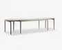 Et langt, rektangulært bord med en lys træfinish. Bordet har rene, lige linjer og seks slanke ben, hvilket giver det et minimalistisk og moderne udtryk. Overfladen er glat og rummelig, velegnet til at sidde mange personer eller til brug ved større sammenkomster.
