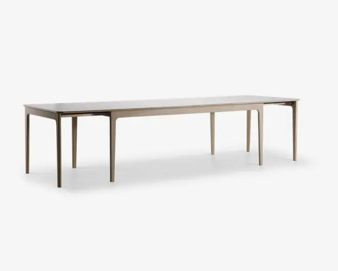 Et langt, rektangulært bord med en lys træfinish. Bordet har rene, lige linjer og seks slanke ben, hvilket giver det et minimalistisk og moderne udtryk. Overfladen er glat og rummelig, velegnet til at sidde mange personer eller til brug ved større sammenkomster.