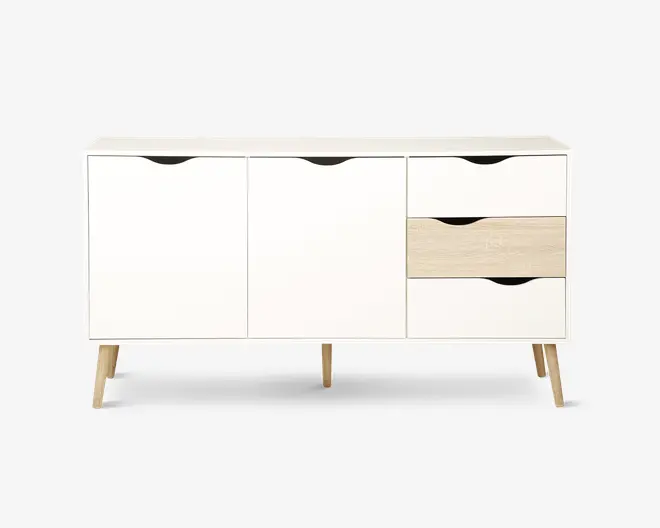 Rektangulært skænk med moderne, minimalistisk design, hvid finish og detaljer i naturtræ. Den har to store skabslåger til venstre og tre skuffer til højre, hvor den midterste skuffe er i lys træfarve. Skuffer og låger har udskårne greb for nem åbning. Skænken står på fire skråtstillede træben.