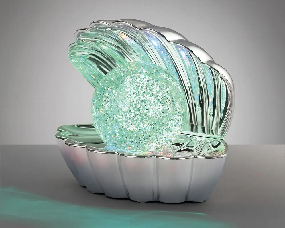En dekorativ genstand formet som en åben muslingeskal med en blank, metallisk sølvfinish. Indeni skallen ligger en stor, rund kugle fyldt med glitrende glimmer og oplyst af bløde, flerfarvede LED-lys, hvilket skaber en glødende effekt. Skalens inderside reflekterer også lyset og forstærker det funklende udseende. Det samlede design er elegant og iøjnefaldende, velegnet som natlampe eller pyntegenstand.