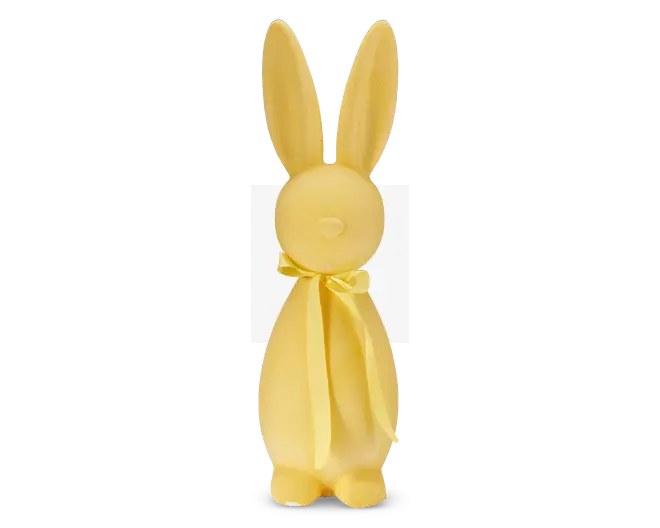 En glat, mat gul figur formet som en kanin med lange opretstående ører, et rundt hoved med en lille cirkulær næse og en enkel krop. Kaninen har et matchende gult bånd bundet i en sløjfe omkring halsen. Designet er minimalistisk uden ansigtsdetaljer udover næsen, og overfladen ser ud til at være lavet af et solidt materiale.
