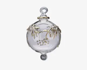 En klar, kugleformet glaspynt med en løkke øverst til ophængning. Overfladen er dekoreret med fine grene og blade i guldfarve samt små guldfarvede prikker samlet i en klynge. Pynten har en glat, blank finish og en lille rundet udvidelse i bunden.