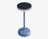 En moderne, cylindrisk bordlampe med mat blå finish. Lampen har en rund, flad top med en sort, tekstureret overflade, sandsynligvis en berøringsfølsom eller solpanel. Der er en gennemsigtig ring under toppen, som fungerer som lyskilde. Lampen har en slank, lige stang og en bred, stabil fod med et diskret tænd/sluk-symbol.