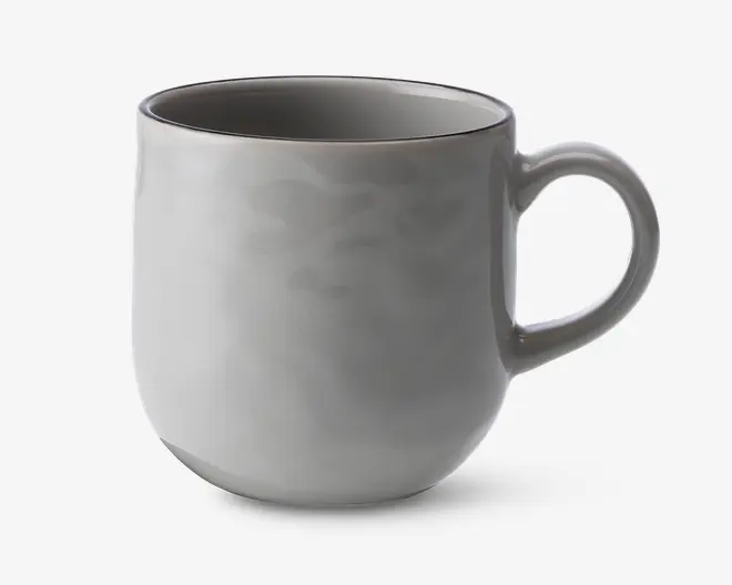 En glat, rund keramikkop med en blank lysegrå overflade. Koppen har et behageligt, buet håndtag og en let tilspidset bund, hvilket giver et moderne og minimalistisk udtryk. Indersiden er også glaseret i samme lysegrå farve, og kanten er diskret markeret.