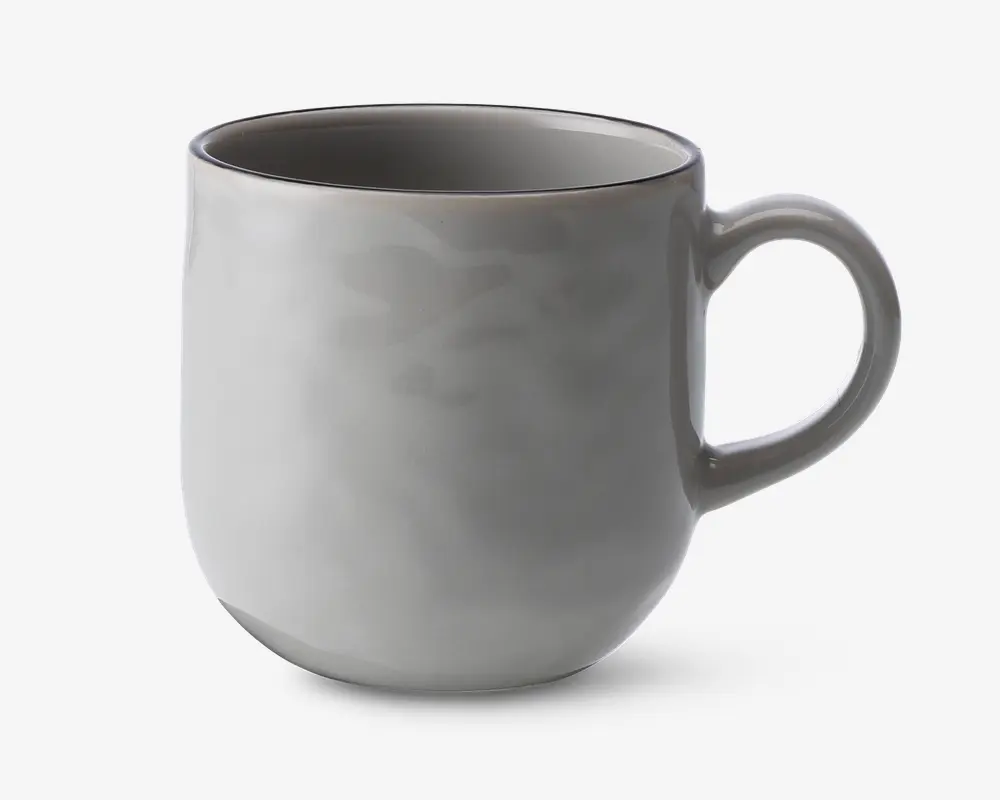 En glat, rund keramikkop med en blank lysegrå overflade. Koppen har et behageligt, buet håndtag og en let tilspidset bund, hvilket giver et moderne og minimalistisk udtryk. Indersiden er også glaseret i samme lysegrå farve, og kanten er diskret markeret.