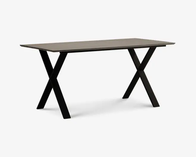 Rektangulært bord med en lys, glat bordplade og solide sorte metalben, der er krydset i et X-formet design i hver ende. Bordet har et minimalistisk og moderne udtryk og giver en rummelig overflade, der egner sig til både spisning, arbejde eller andre aktiviteter.