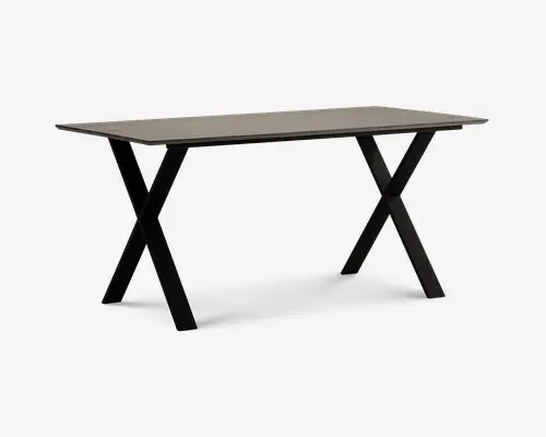 Rektangulært bord med en lys, glat bordplade og solide sorte metalben, der er krydset i et X-formet design i hver ende. Bordet har et minimalistisk og moderne udtryk og giver en rummelig overflade, der egner sig til både spisning, arbejde eller andre aktiviteter.