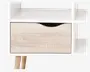 Et moderne natbord med hvid ramme, der har en enkelt skuffe i lyst træ med et buet udskåret greb øverst i midten. Natbordet har åbne hylder på begge sider og står på to skrå træben, hvilket giver det et skandinavisk inspireret design.