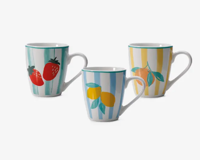 Sæt med tre keramikkrus, hver med unikt håndmalet frugtmotiv og lodrette striber. Ét krus har røde jordbær med grønne blade på turkise striber, et andet har gule citroner med grønne blade på lyseblå striber, og det tredje viser en appelsin med grønne blade på gule striber. Alle krus har hvid baggrund, buet hank og en turkis kant.