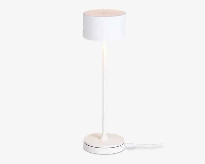 En moderne, minimalistisk lampe med en cylindrisk hvid lampeskærm, en slank lige stang og en rund fod. Lampen har et rent, helt hvidt udseende og en synlig ledning, der går ud fra bunden. Designet er stilrent og enkelt, velegnet til moderne indretning.