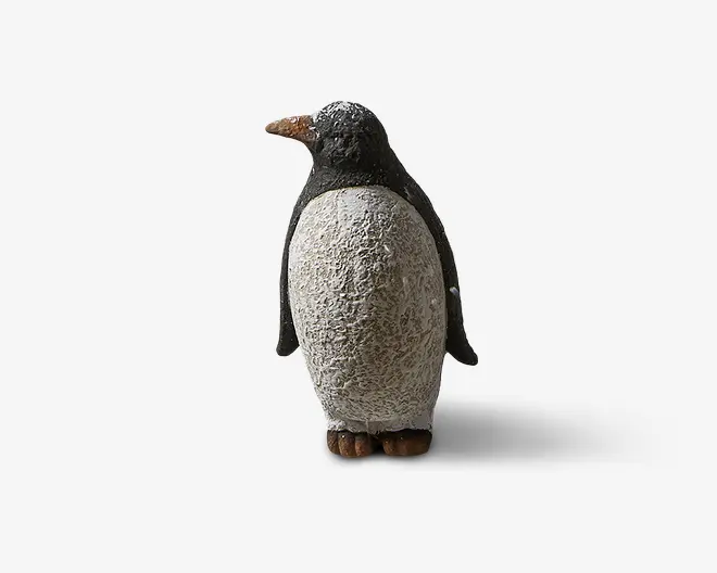 En dekorativ pingvinfigur med en tekstureret hvid krop og glat sort hoved og vinger. Næbbet er orange med en let ru overflade, og fødderne er brune. Kroppens overflade efterligner fjer og giver et realistisk udseende. Figuren står oprejst og er designet med sans for detaljer, hvilket gør den velegnet til udstilling.