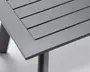 Nærbillede af et bordhjørne med mat, mørkegrå overflade. Bordpladen har et lameldesign med jævnt fordelte, vandrette paneler, og rammen er lavet af solidt metal. Benene er firkantede og robuste, hvilket giver stabil støtte.