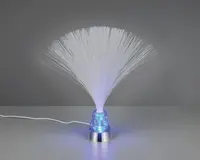 En dekorativ lampe med en sølvfarvet bund og en kegleformet, gennemsigtig blå sektion fyldt med glimmer. Tynde, hvide fiberoptiske tråde spreder sig ud fra toppen og danner en bred, fjerlignende effekt. Lampen udsender et blødt blåt skær, der oplyser fibrene og glimtet i bunden. En hvid ledning går ud fra bagsiden.