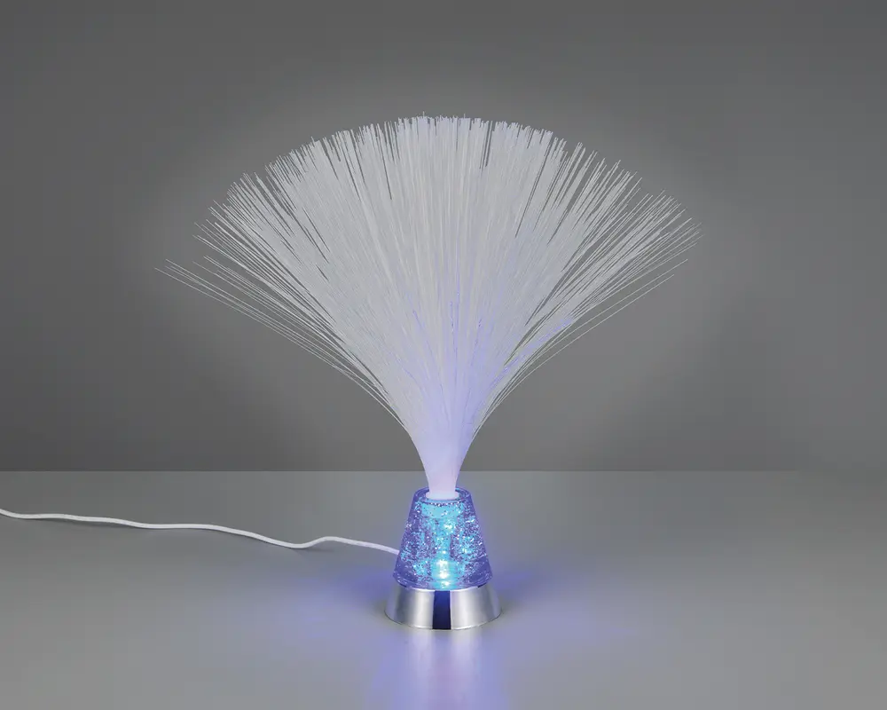 En dekorativ lampe med en sølvfarvet bund og en kegleformet, gennemsigtig blå sektion fyldt med glimmer. Tynde, hvide fiberoptiske tråde spreder sig ud fra toppen og danner en bred, fjerlignende effekt. Lampen udsender et blødt blåt skær, der oplyser fibrene og glimtet i bunden. En hvid ledning går ud fra bagsiden.